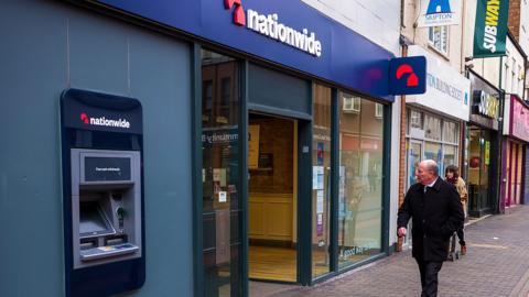 A man walking past a Nationwide branch