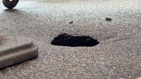 A tarmac road with a hole the size of a football.