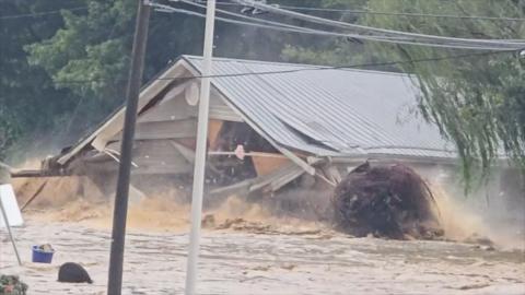 A house floats down a muddy river collapsing