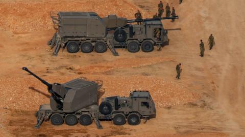 Israeli soldiers next to artillery vehicles near the Israel-Lebanon border, in northern Israel