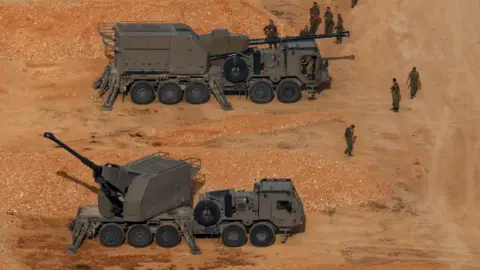Israeli soldiers next to artillery vehicles near the Israel-Lebanon border, in northern Israel