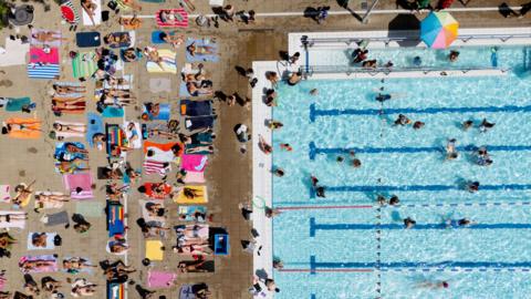 Aerial shot of people sunbathing and swimming at London Fields Lido