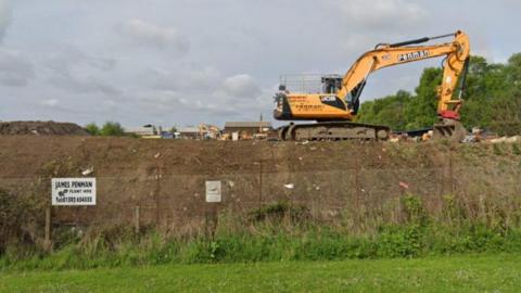 A yellow Penman digger behind a fence on the former James Penman Plant Hire site in Kirkcaldy.