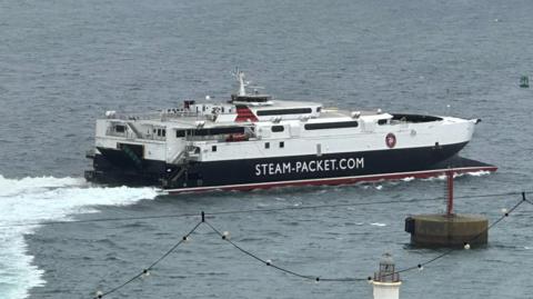 The fast craft Manannan sailing out of Douglas Harbour. It is white, black and red and had STEMA-PACKET.COM written on the said.