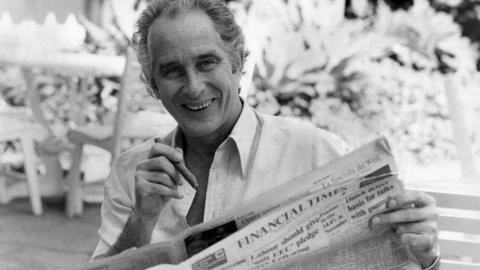 Ronald Biggs smoking a cigar and reading the paper