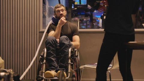 Ollie Thorn training for Everest. He is in a wheelchair, with an oxygen mask close to his face.