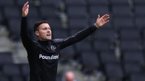 Walsall manager Mat Sadler waves his arms from the dugout during a match