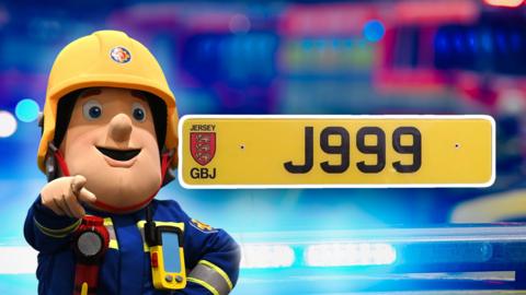 A composite image of Fireman Sam with a number plate next to him that says J999