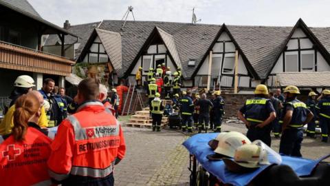 Firefighters, medical and THW (Federal Agency for Technical Relief) staff wait outside, after a hotel partially collapsed overnight near the banks of Germany's river Moselle in Kroev, Germany, August 7, 2024. 