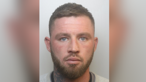 A police custody photo of William Free. He has short brown hair, a beard, ear piercings and a tattoo on his neck.