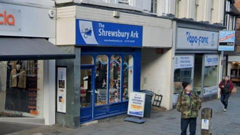 The front of a shop with a blue sign which reads Shrewsbury Ark