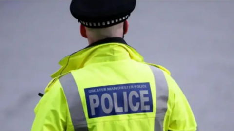 A police officer, wearing a high-vis jacket, with the word 'police' in capital letters on a blue background on the back of the jacket.