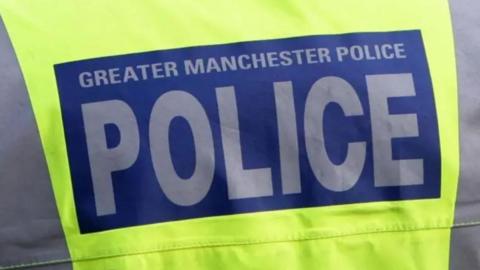 Back of a police officer's hi-vis jacket with the words 'Greater Manchester Police'