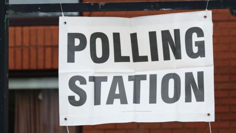 A sign reading "Polling Station" hung outside a brick building