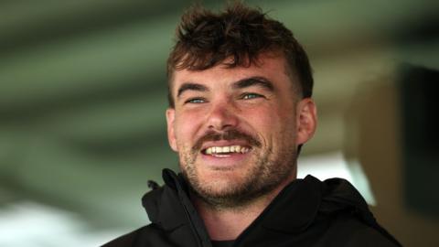 George Furbank smiles while wearing a black coat