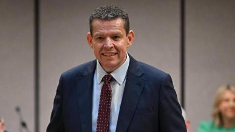 Rhun ap Iorwerth wearing a suit, with a red tie