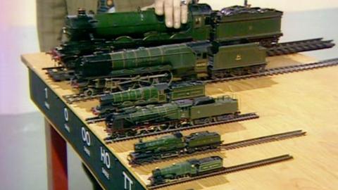Model trains of different sizes lined up on a table, from gauge 1 to gauge TT
