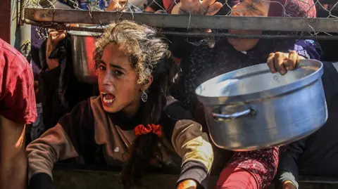 Displaced Palestinians including women and children living in tents receive food distributed by aid organizations in al Mawasi district of Khan Yunis, Gaza on May 30, 202