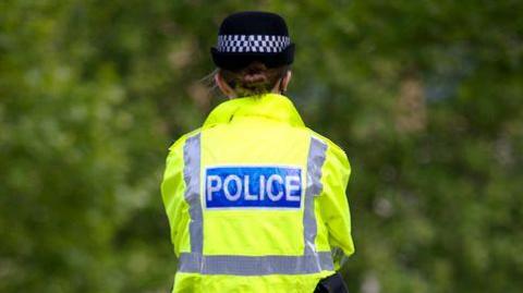 A woman police officer wearing a hi-vis jacket is on duty.