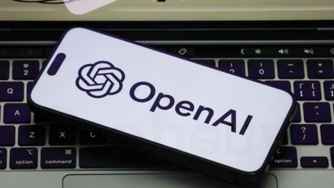 The OpenAI logo on a white phone backgorund, the phone is on a laptop keyboard