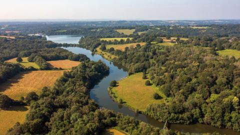 An aerial image showing a winding river running through a collection of fields and trees