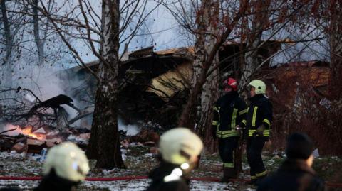 Wreckage of a crashed plane with emergency services staff at the scene