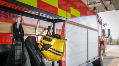 A close up of a fire truck with some a helmet and handles of a bag hanging off the side