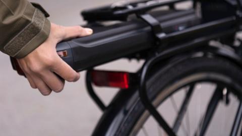 Woman putting a battery on to an ebike.