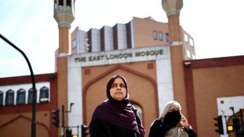 a woman looks anxious as she leaves the East London Mosque during the riots in August