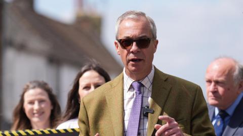 Nigel Farage in dark glasses and a mustard coloured suit on a walkabout