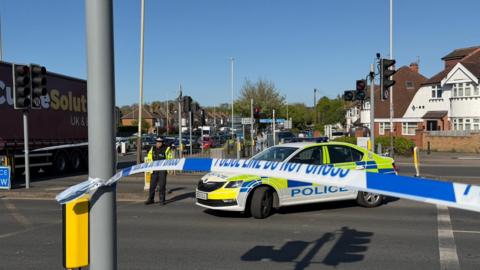 Police car and officer behind a cordon