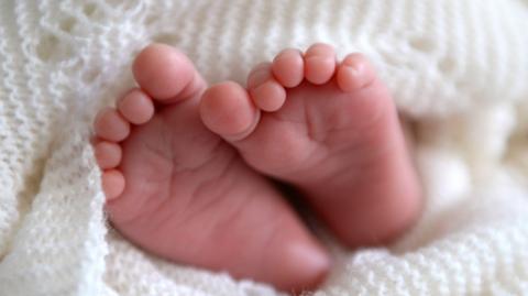 A new born baby's feet peeking out of a shawl