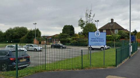 A sign on a fenced off grass verge next to a car park says 'Ditton Primary Academy School'. 