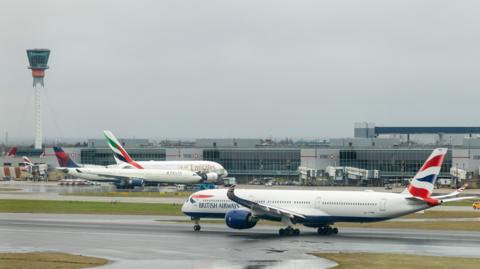 Two British Airways and one Emirates planes on Heathrow Airport runway. 