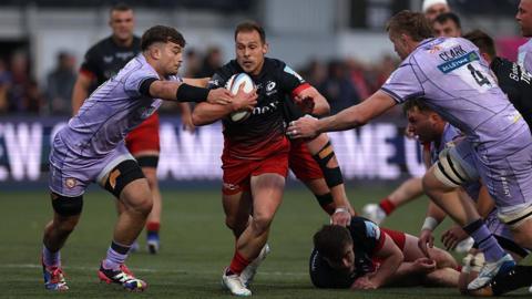 Saracens' Ivan van Zyl runs with the ball in his right hand as a Gloucester player (left) stretches his arms out towards him in an attempt to tackle