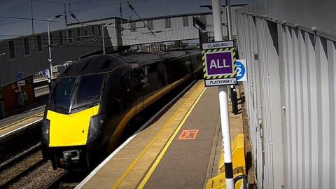 CCTV of a black and yellow train next to a platform