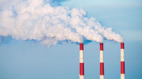 Red and white striped chimneys with white smoke coming out of the top.