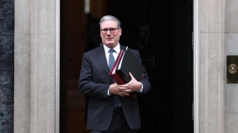 Sir Keir Starmer in front of Downing Street. He is holding two folders in his hands