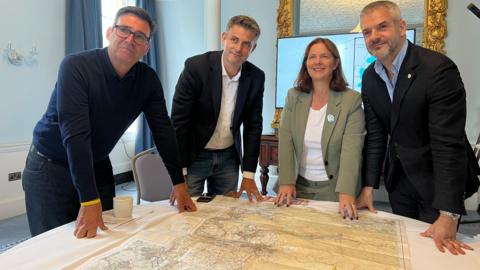 Four people gathered around a round table with a map on it of the Peak District 