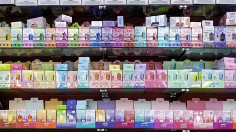 Three shelves stacked with colourful vape products.