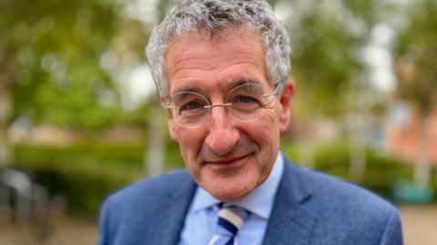 Head and shoulders image of Peter Prinsley MP. He is wearing a blue jacket, shirt and striped tie.