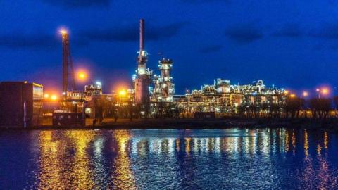 The St Fergus gas terminal in Aberdeenshire, photographed at night, with infrastructure lit up, and reflected in water.