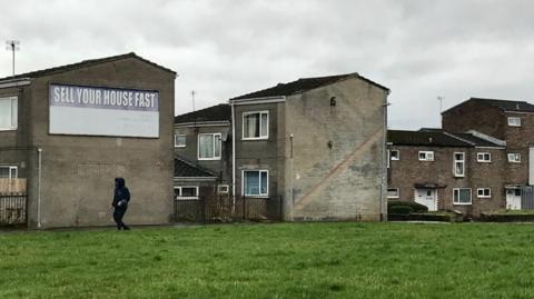 Generic view of dirty-looking run down houses and flats by a strip of grass