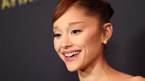 Ariana Grande smiles with hair in bun 