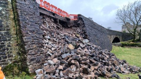 An image showing the bridge collapsed. You can see a large pile of stone rubble against the existing bridge structure.