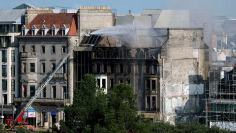 Firefighters dampen down a fire-damaged building