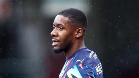 Jovan Malcolm in a Barrow away kit with his head turned to the left