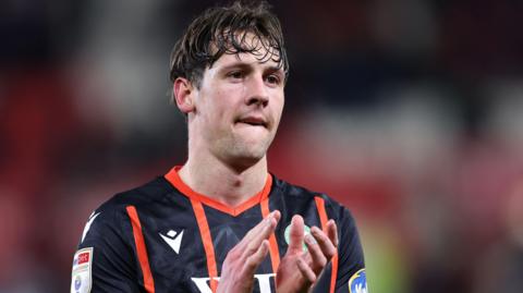 Callum Brittain applauding fans at full time