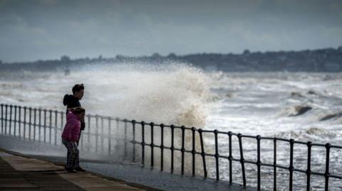 Children brave wind and sea spray on a promenade