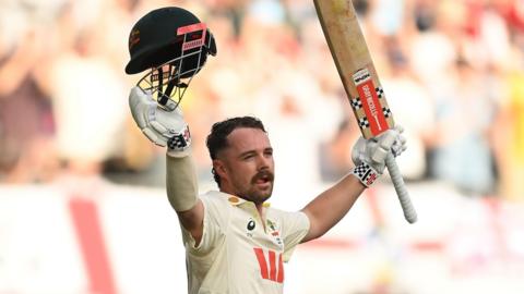 Australia batter Travis Head raises his bat and helmet as he walks off after making 123